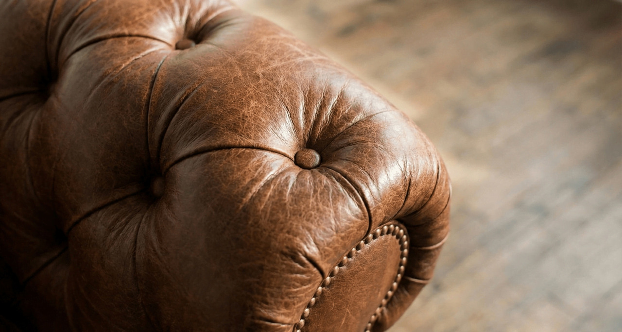 Detailed view of a brown leather Chesterfield arm with button-tufting